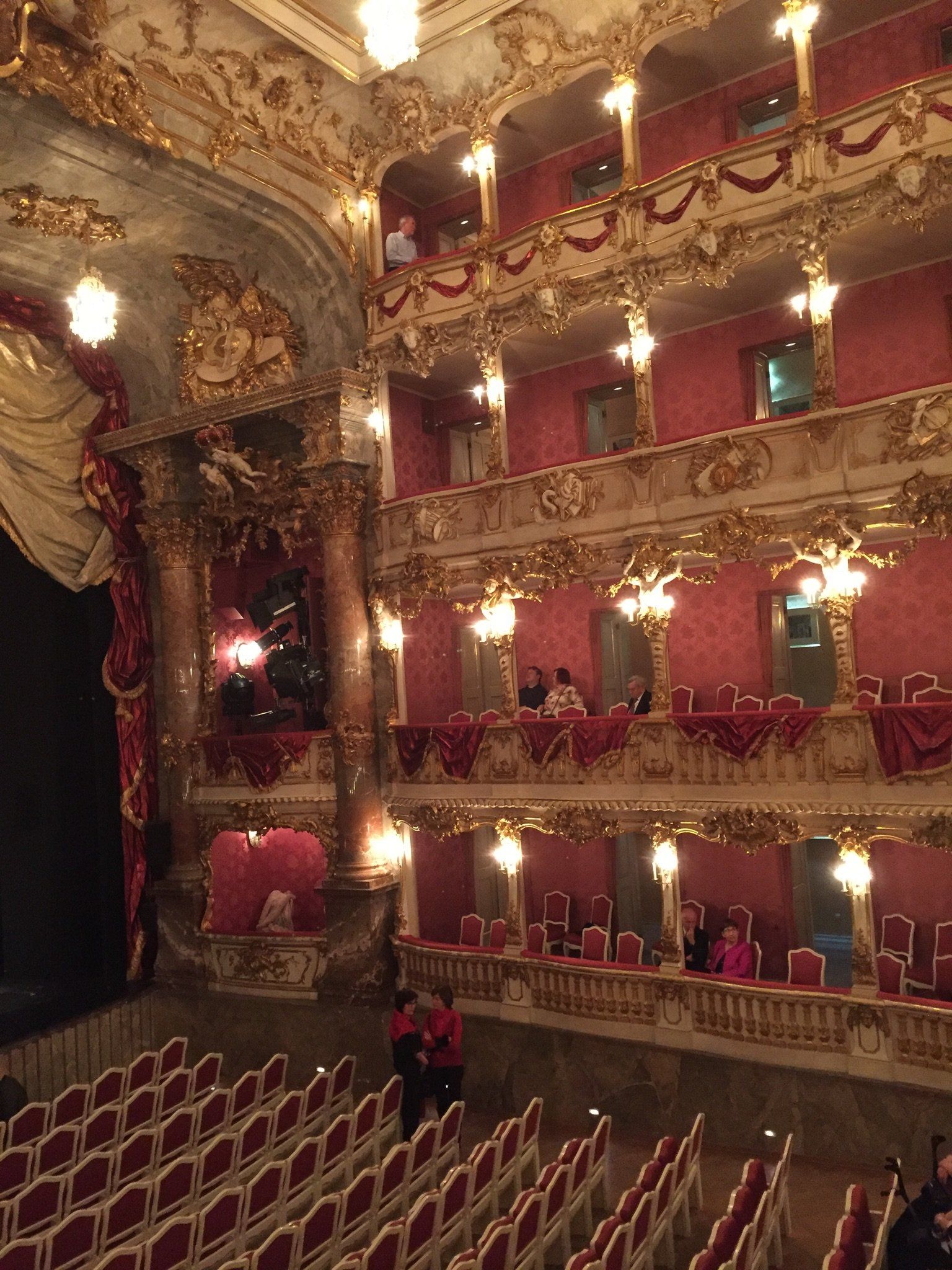 Ein großes Theater mit Reihen roter Sitze und einem Balkon.