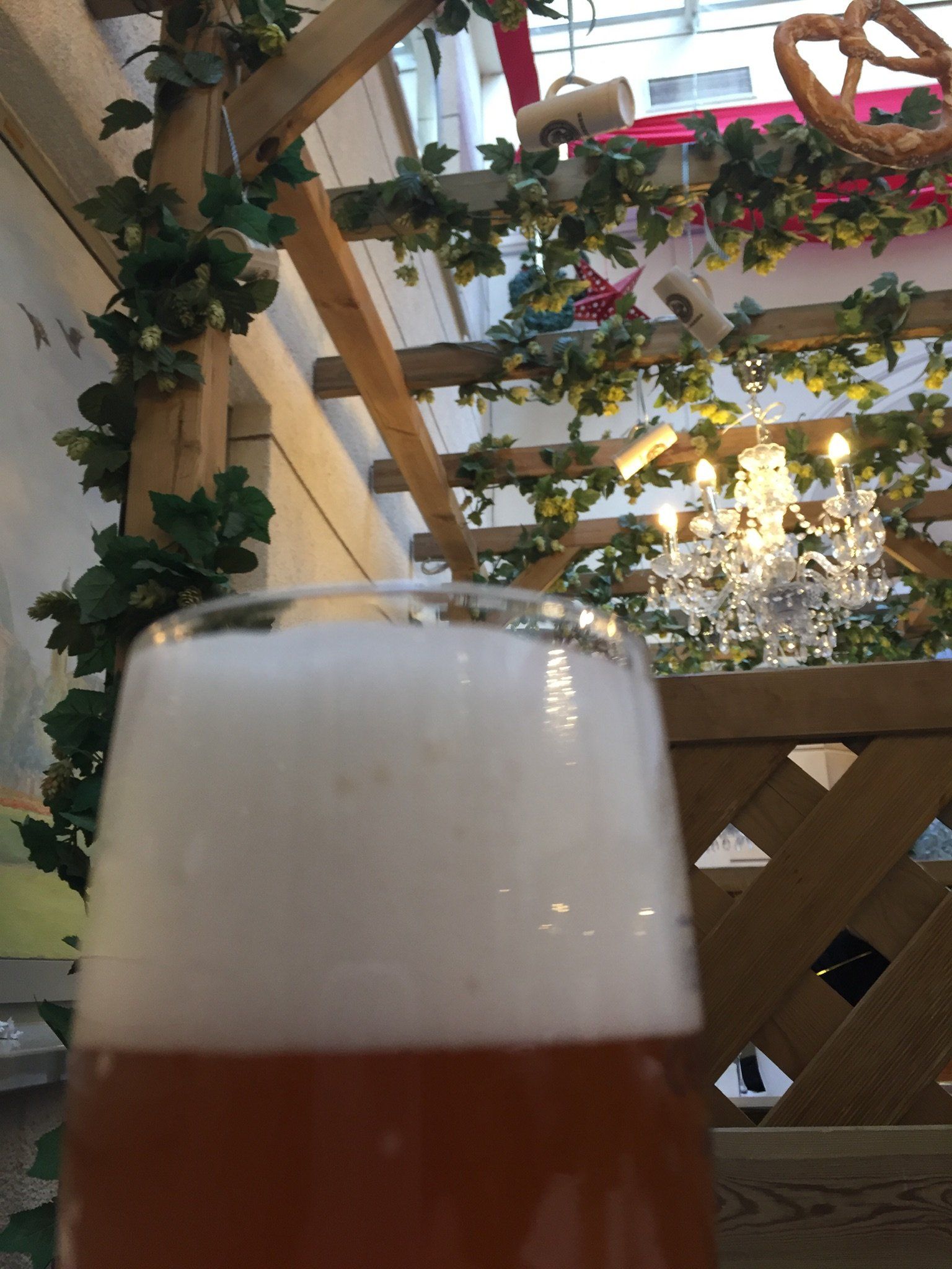 Eine Nahaufnahme von einem Glas Bier mit einem Kronleuchter im Hintergrund