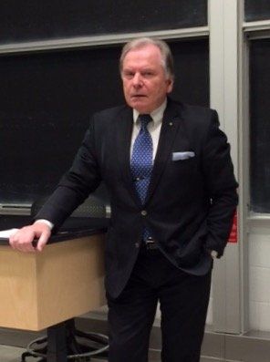 Ein Mann in Anzug und Krawatte steht vor einer Tafel