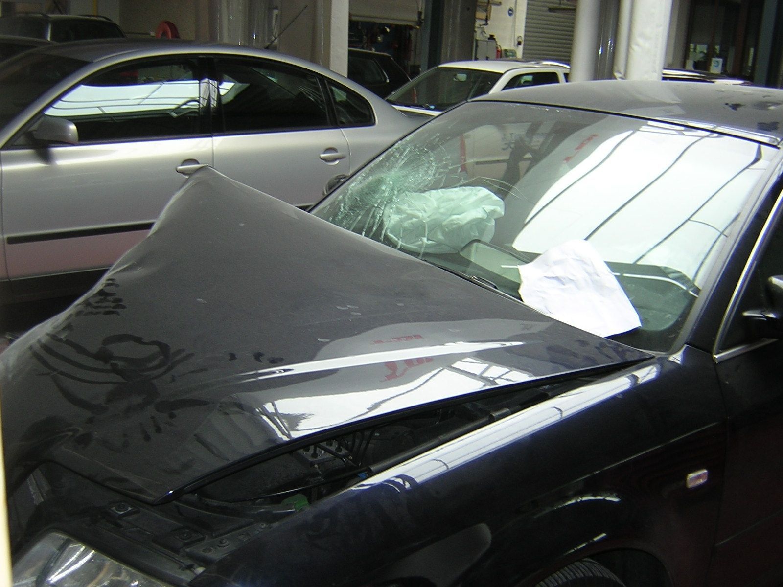 Ein schwarzes Auto mit geöffneter Motorhaube steht neben einem silbernen Auto