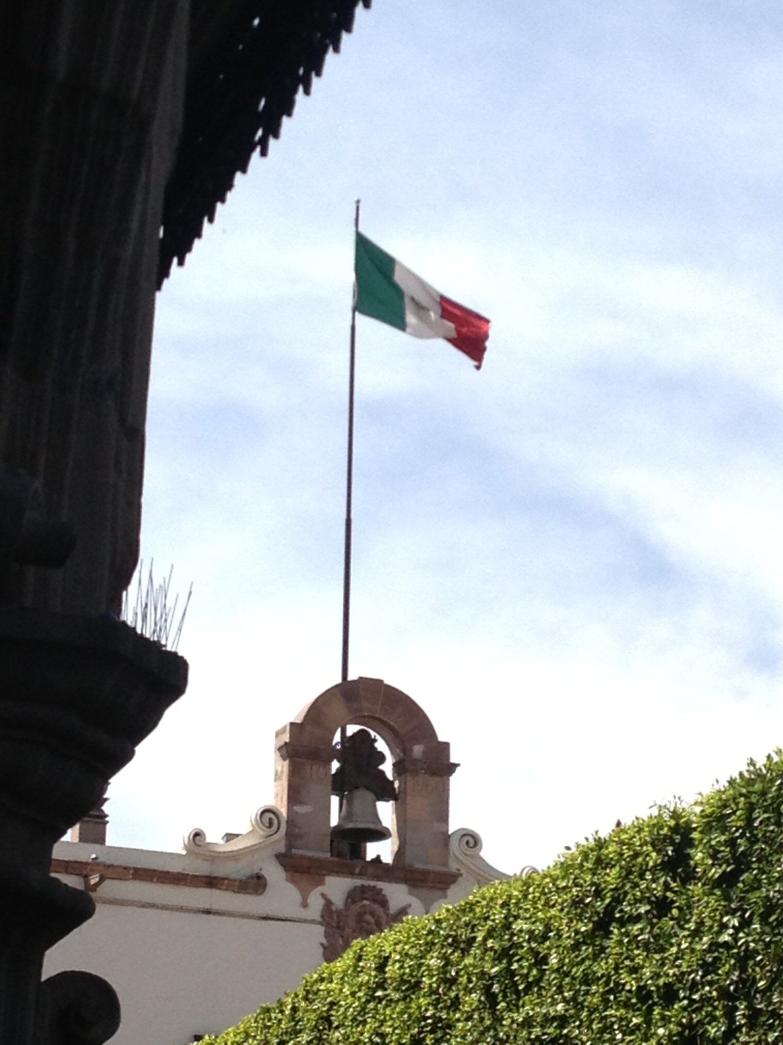 Eine mexikanische Flagge weht im Wind über einem Glockenturm