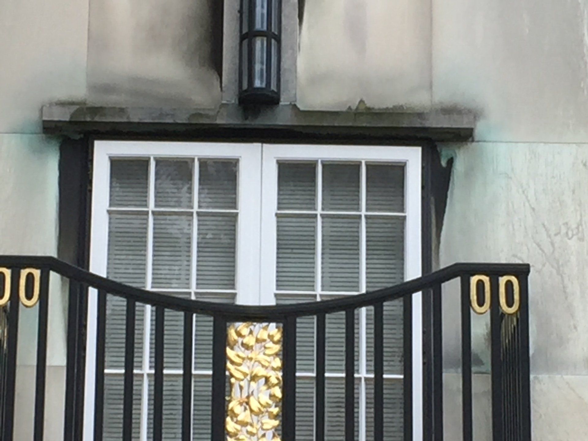 Ein Balkon mit einem schwarzen Geländer an der Seite eines Gebäudes neben einem Fenster.