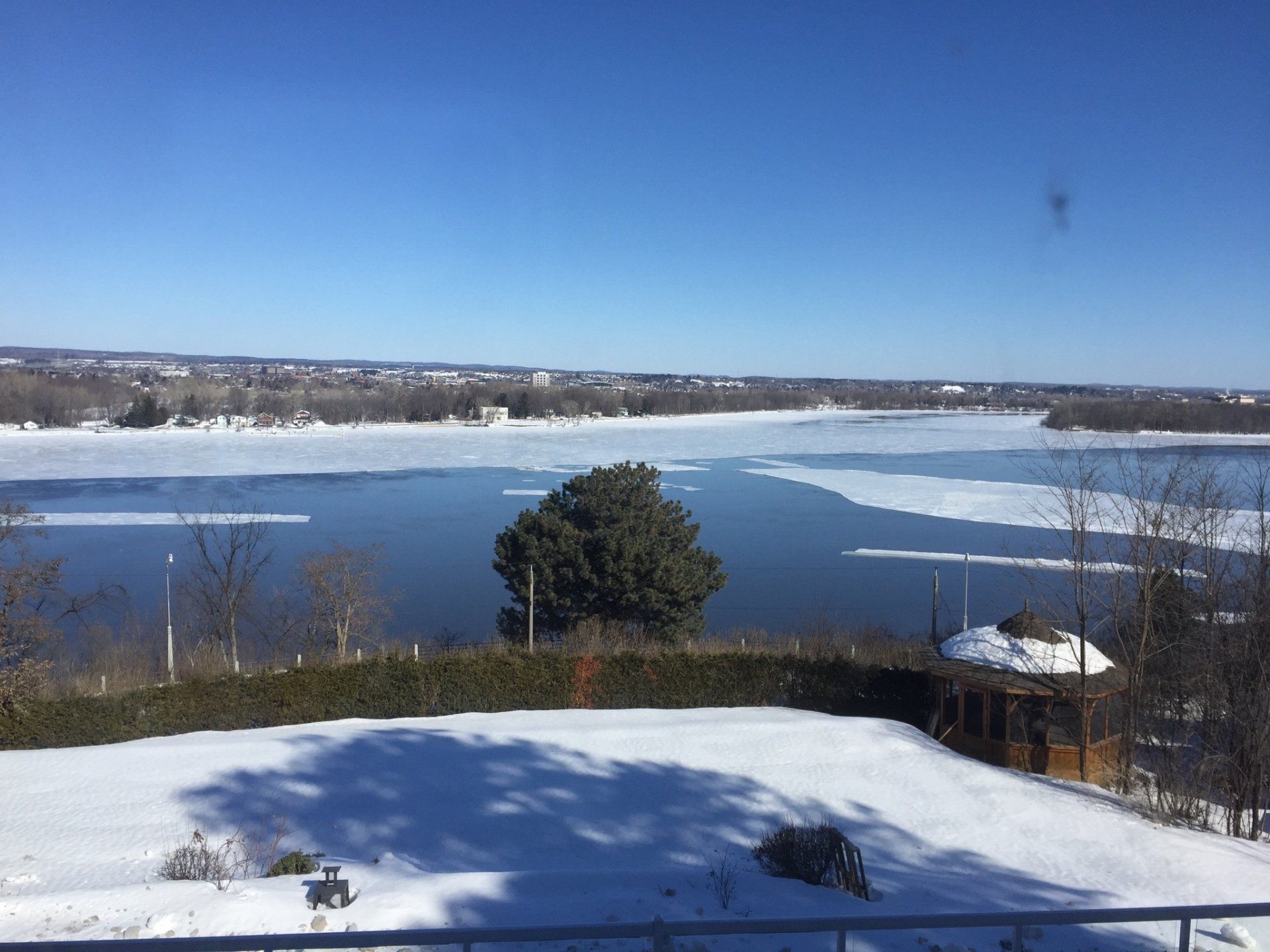 Ein großes Gewässer, umgeben von Schnee und Bäumen