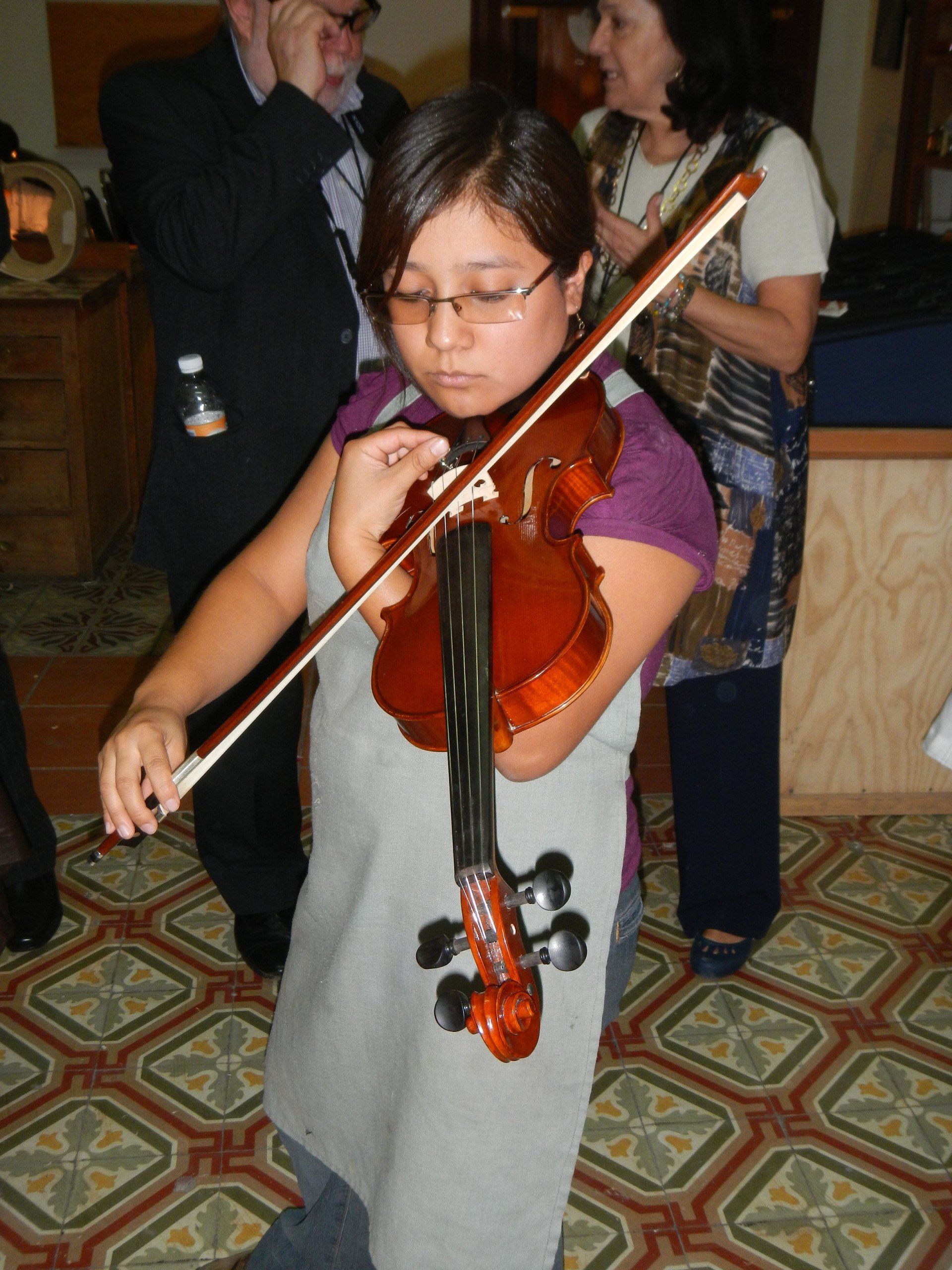 Ein junges Mädchen spielt Geige auf einem gefliesten Boden