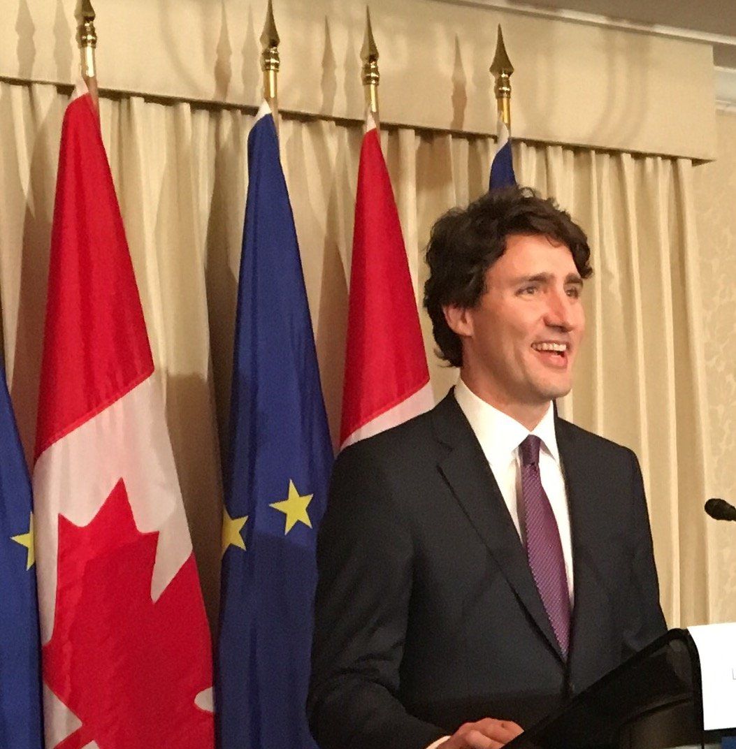 Ein Mann in Anzug und Krawatte steht an einem Podium vor Flaggen