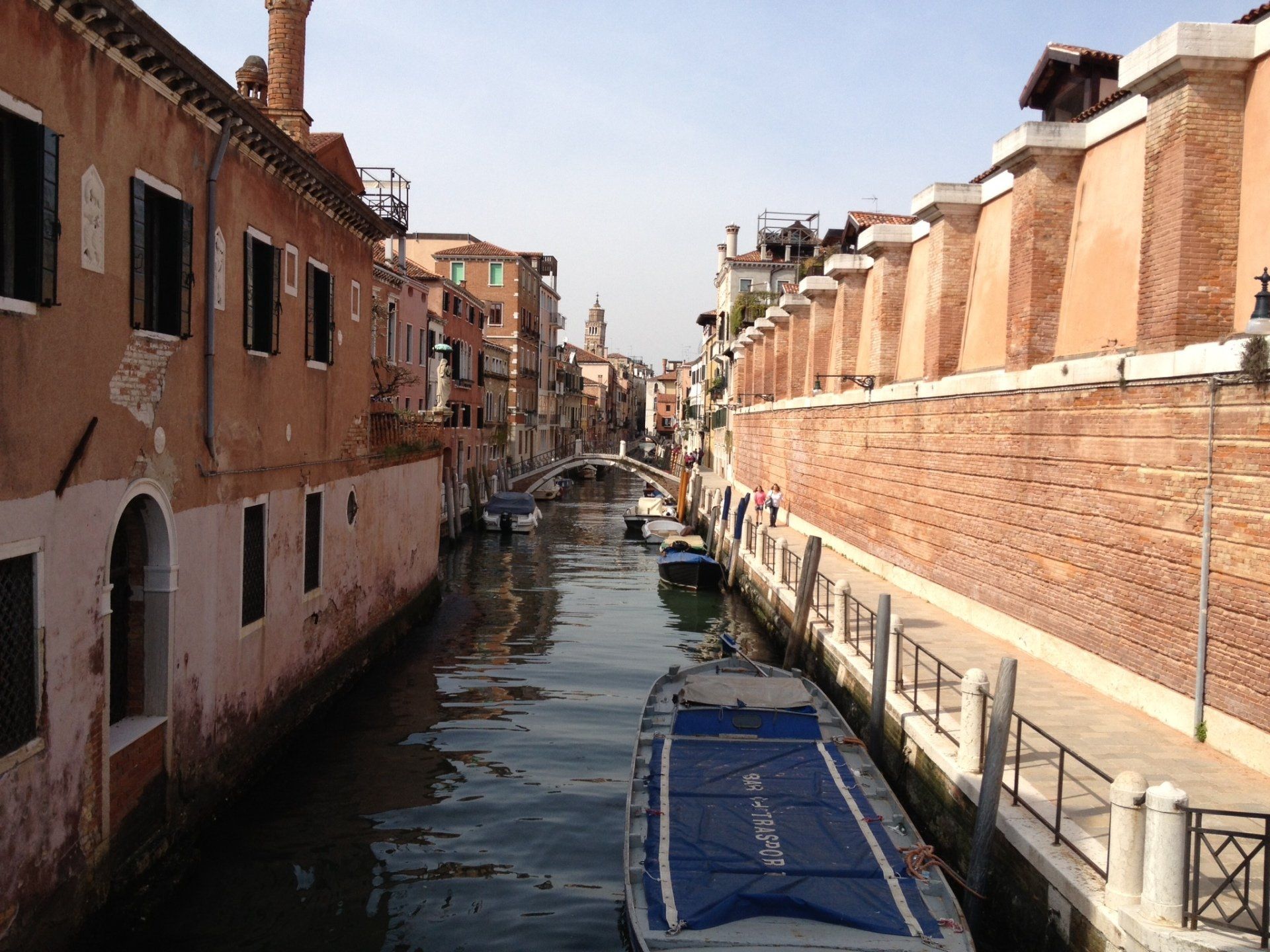 Ein Boot mit einer blauen Plane auf der Rückseite schwimmt einen Kanal hinunter