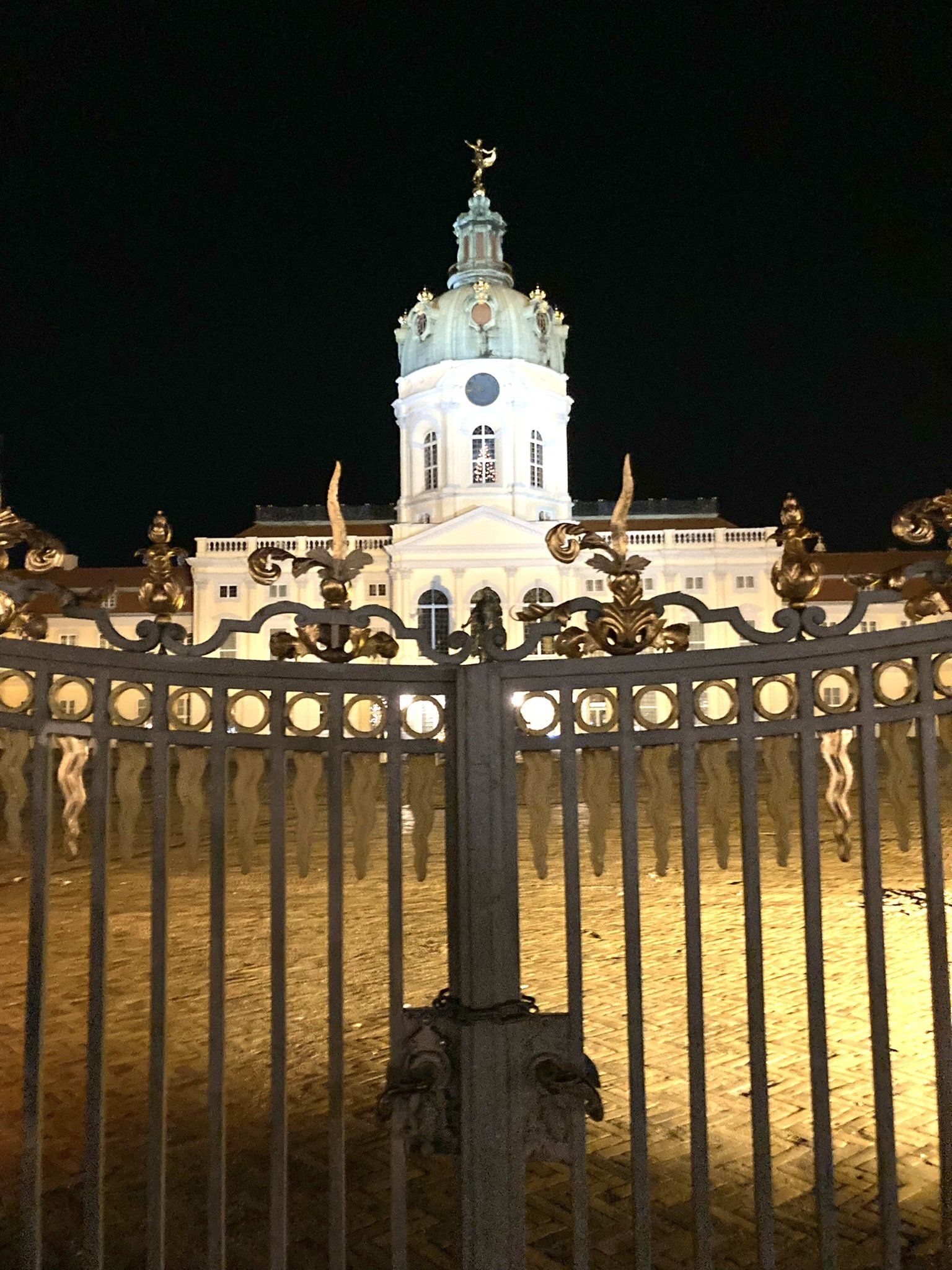 Ein großes Gebäude ist nachts hinter einem Zaun beleuchtet