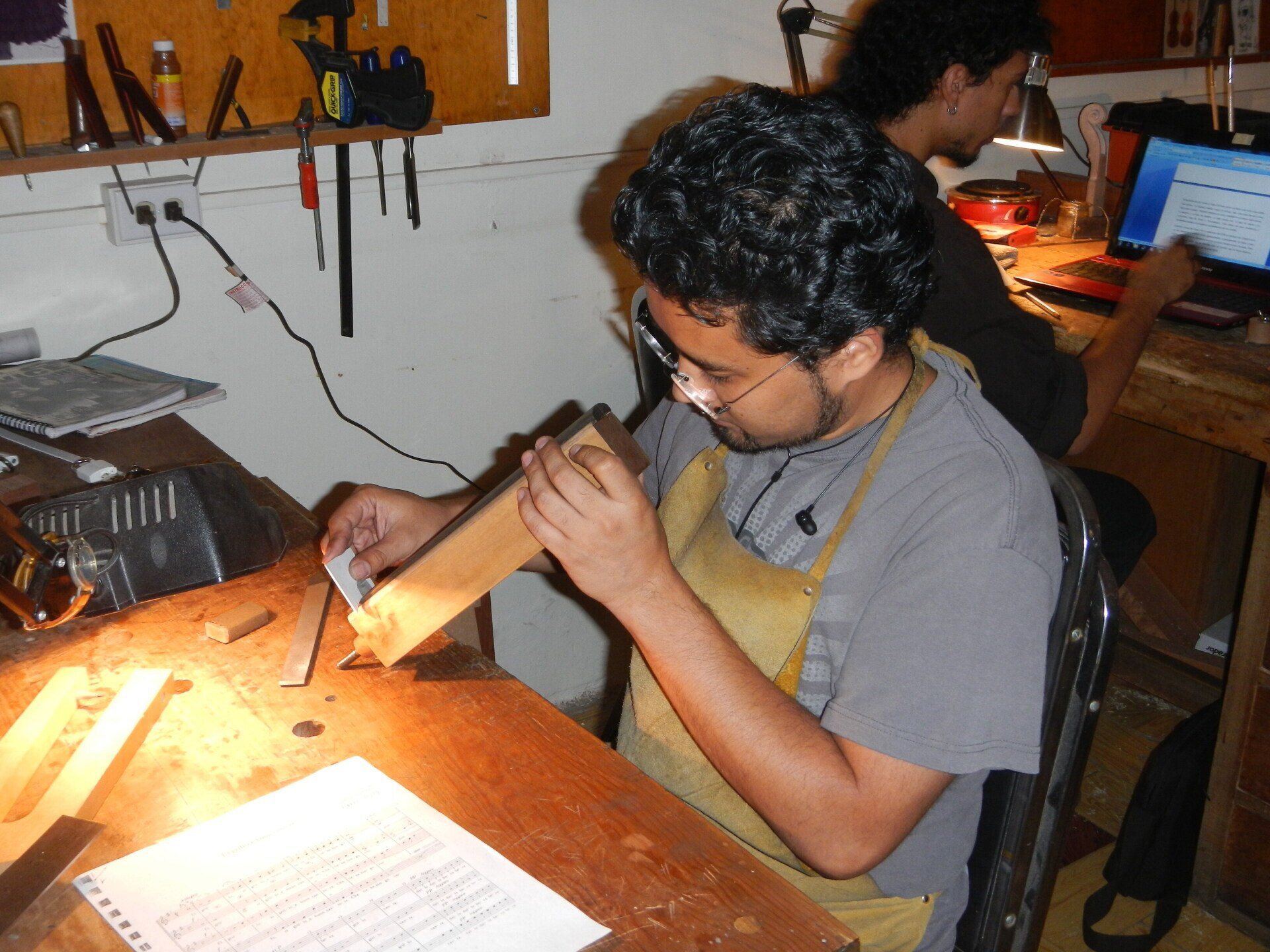 Ein Mann in einer Schürze arbeitet an einem Stück Holz