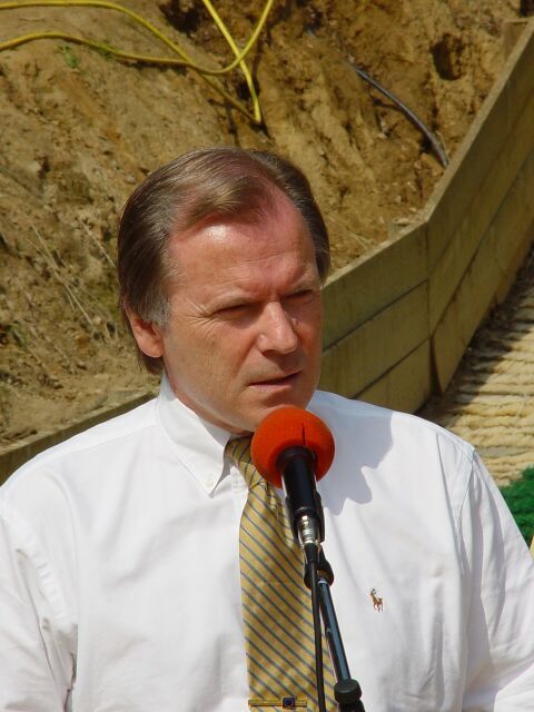 Ein Mann in weißem Hemd und Krawatte spricht in ein Mikrofon