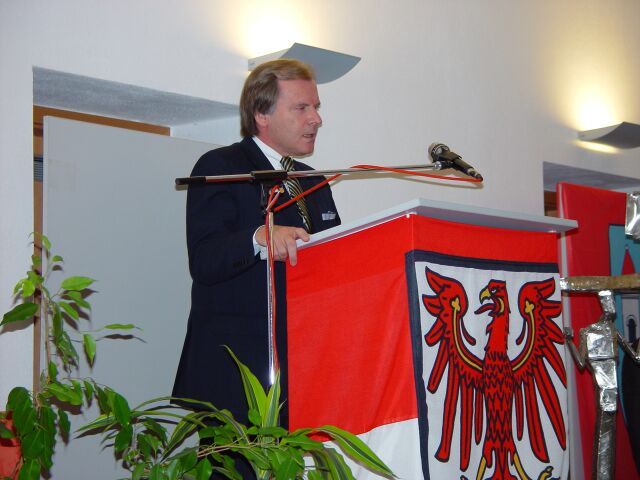 Ein Mann steht auf einem Podium mit einer Flagge hinter ihm