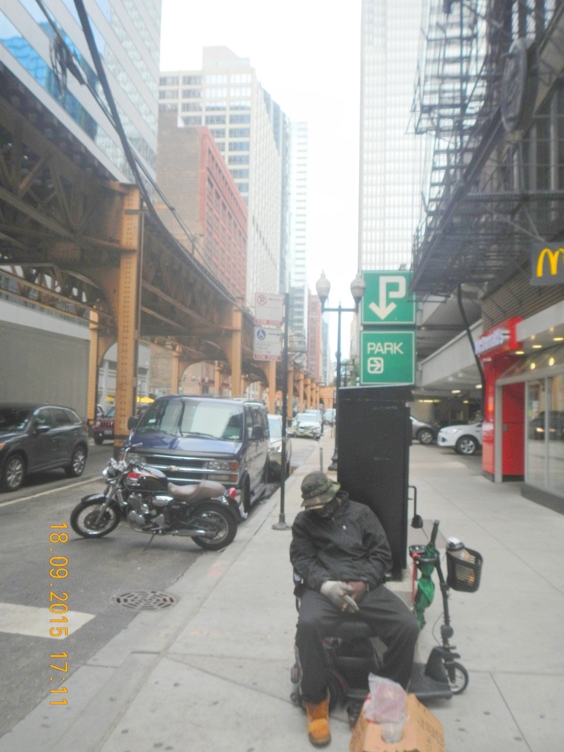 Ein Mann sitzt auf dem Bürgersteig vor einem Parkschild