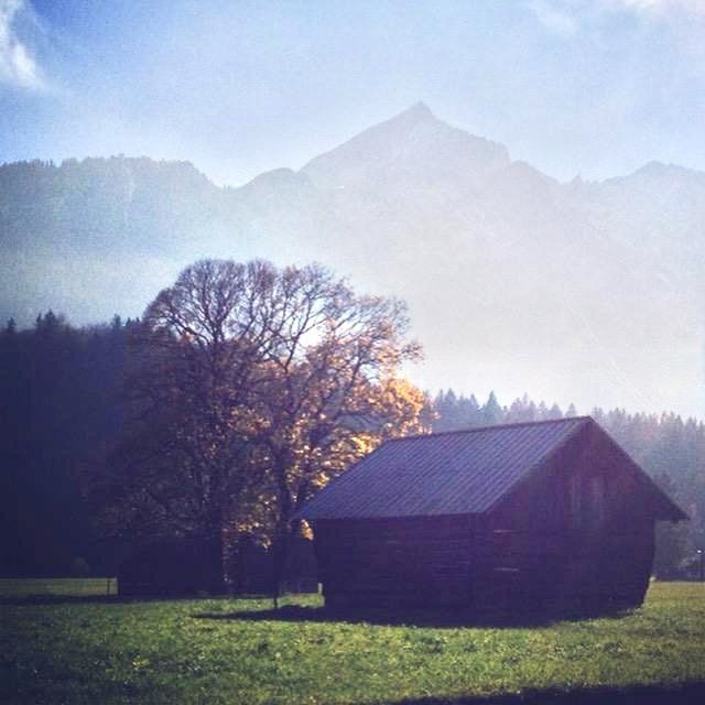 Ein kleines Haus auf einem Feld mit Bergen im Hintergrund