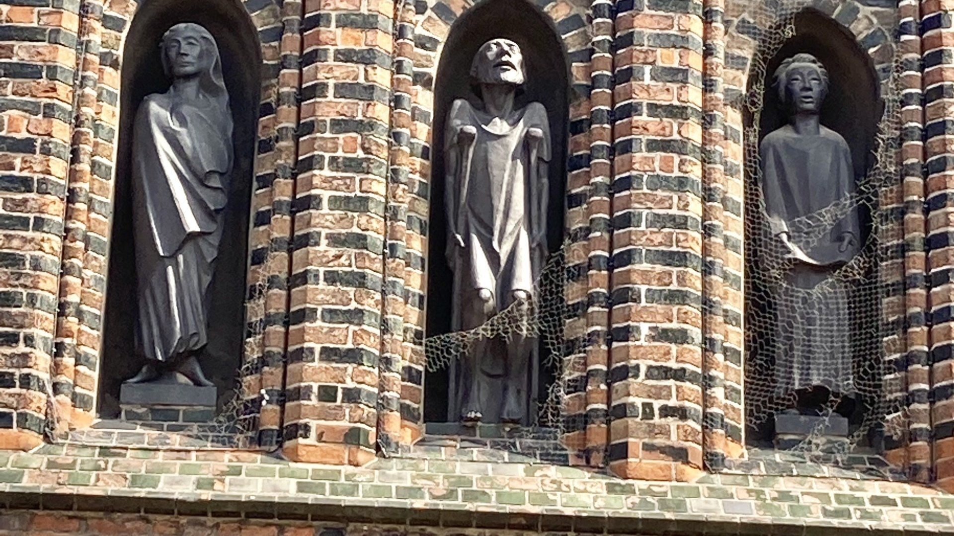Eine Backsteinmauer mit drei Statuen darauf