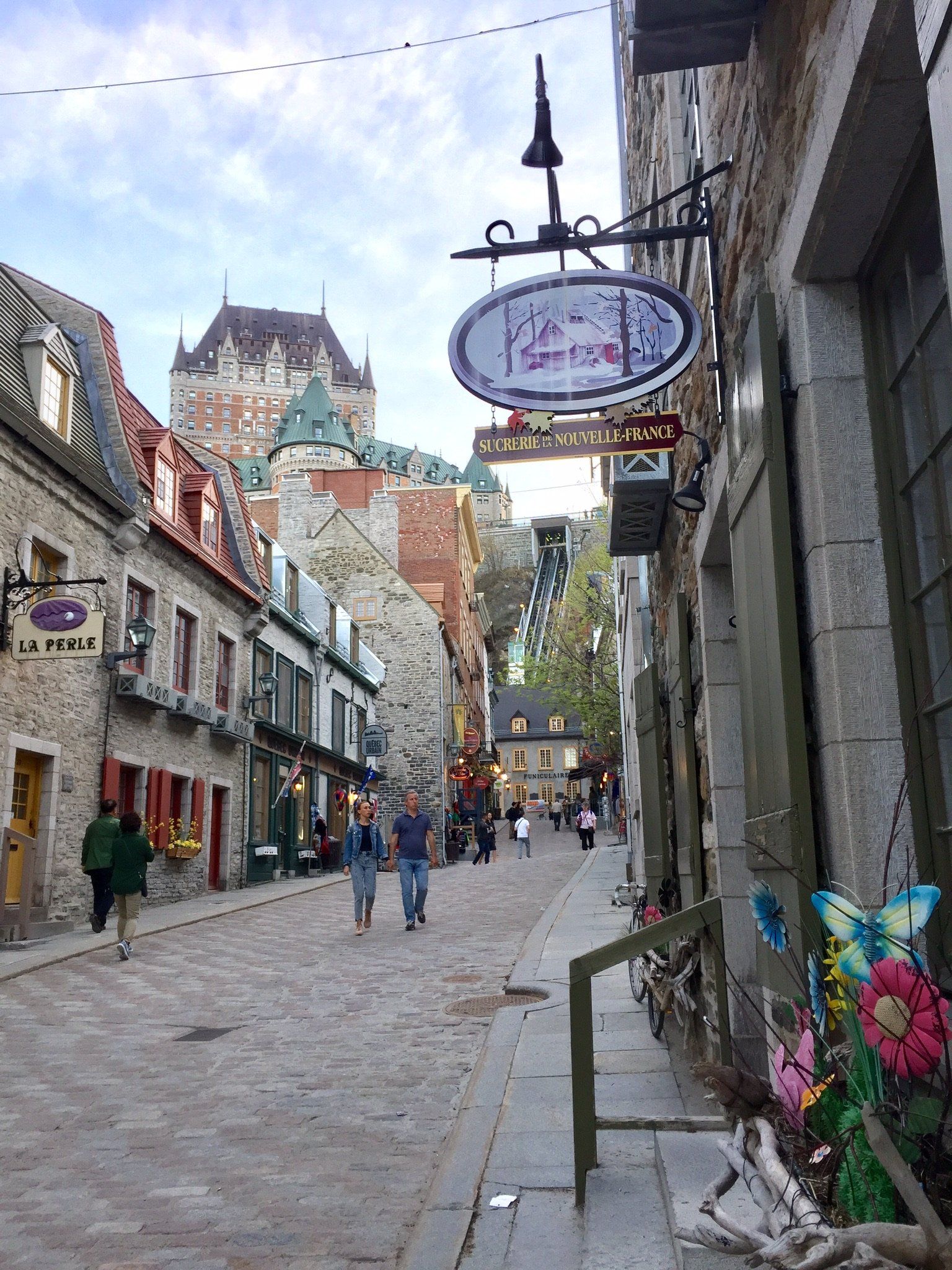 Menschen gehen eine Kopfsteinpflasterstraße in einer Stadt entlang . Im Hintergrund ist ein Schloss zu sehen.