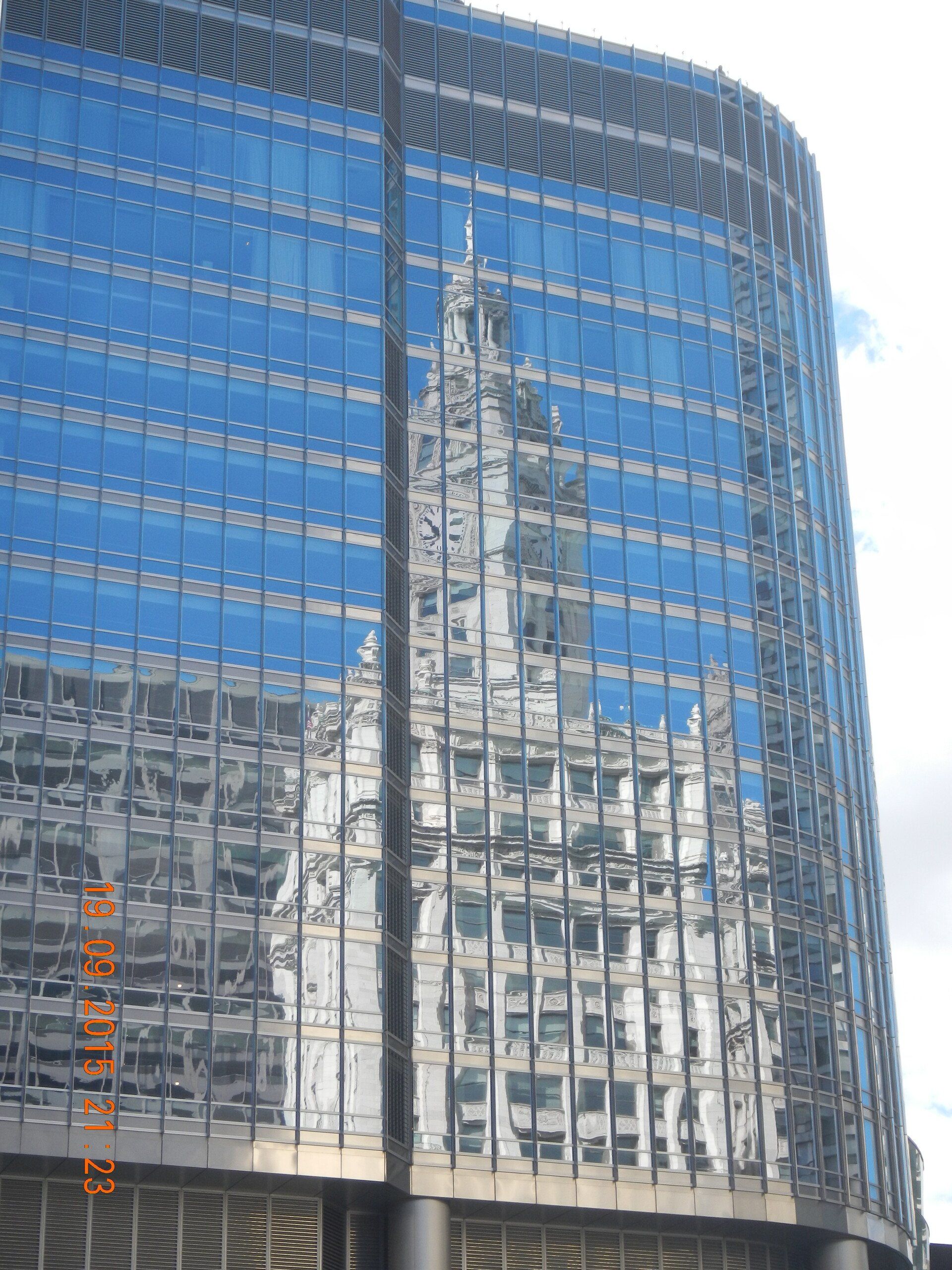 Ein großes Gebäude mit der Spiegelung einer Kirche in den Fenstern.