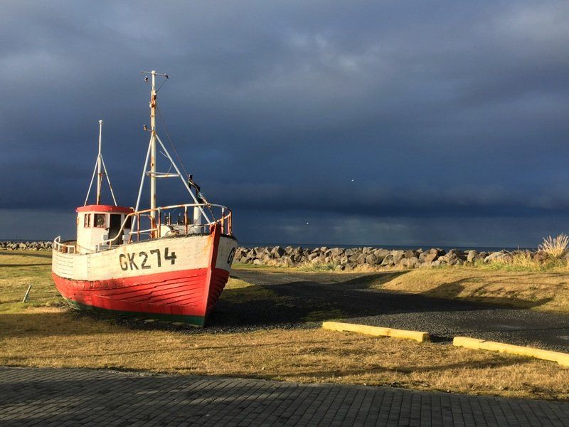 Am Straßenrand parkt ein rot-weißes Boot mit der Nummer GK274.