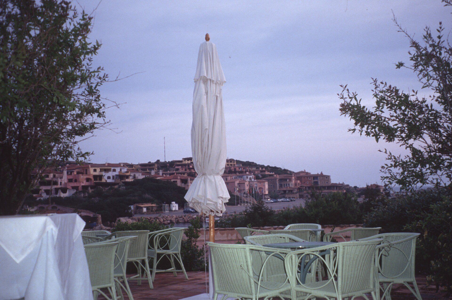 Ein weißer Regenschirm steht vor einem Tisch und Stühlen