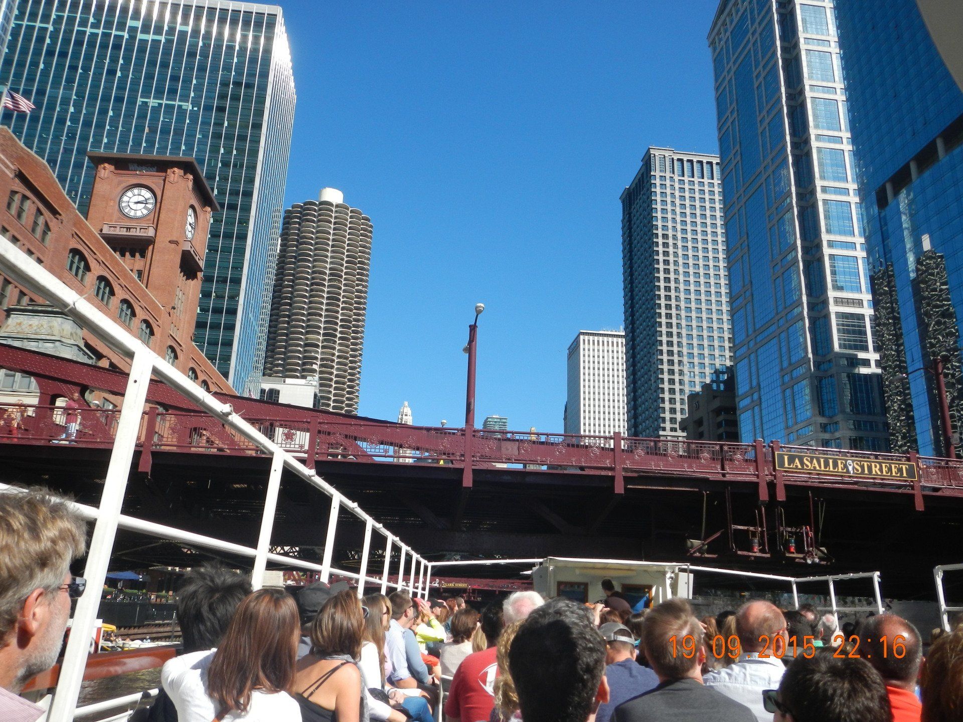Eine Gruppe von Menschen ist auf einem Boot in einer Stadt mit einem Glockenturm im Hintergrund