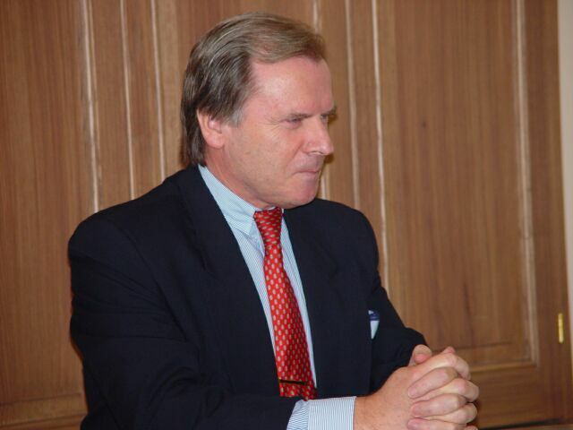 Ein Mann in Anzug und Krawatte mit gefalteten Händen