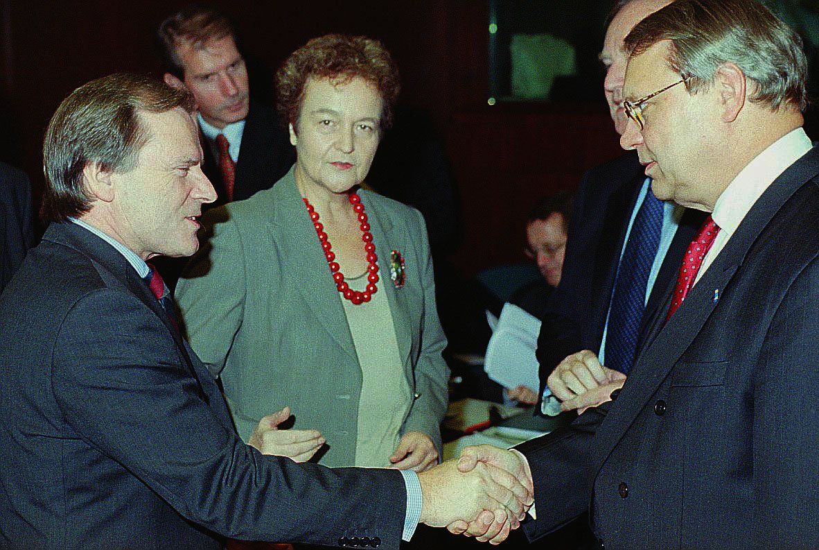 Ein Mann und eine Frau schütteln vor einer Gruppe von Menschen die Hände