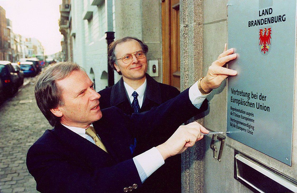 Zwei Männer zeigen auf ein Schild mit der Aufschrift „Landforschung“