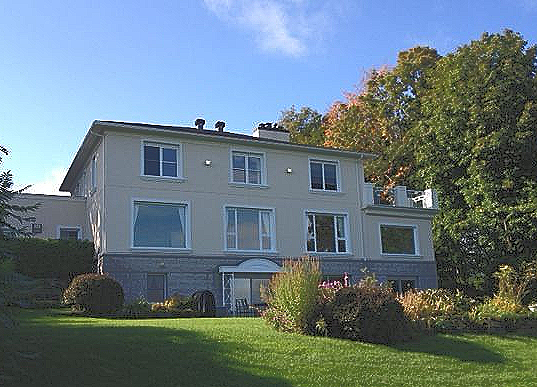 Ein großes Haus mit vielen Fenstern steht auf einem üppigen grünen Rasen.