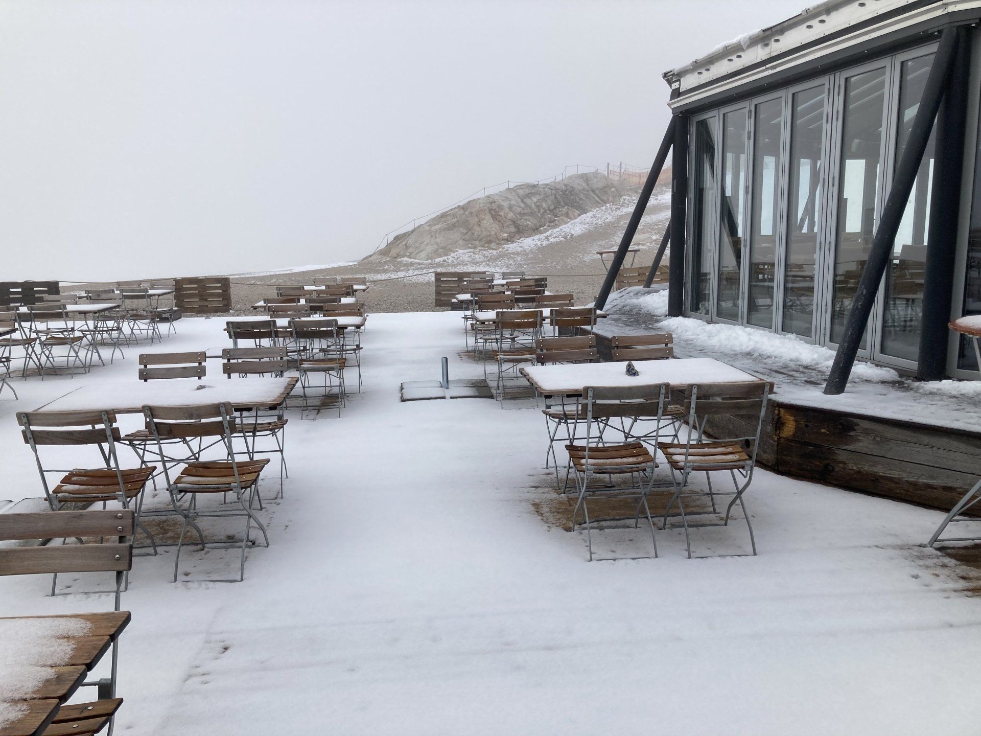 Eine Terrasse mit schneebedeckten Tischen und Stühlen