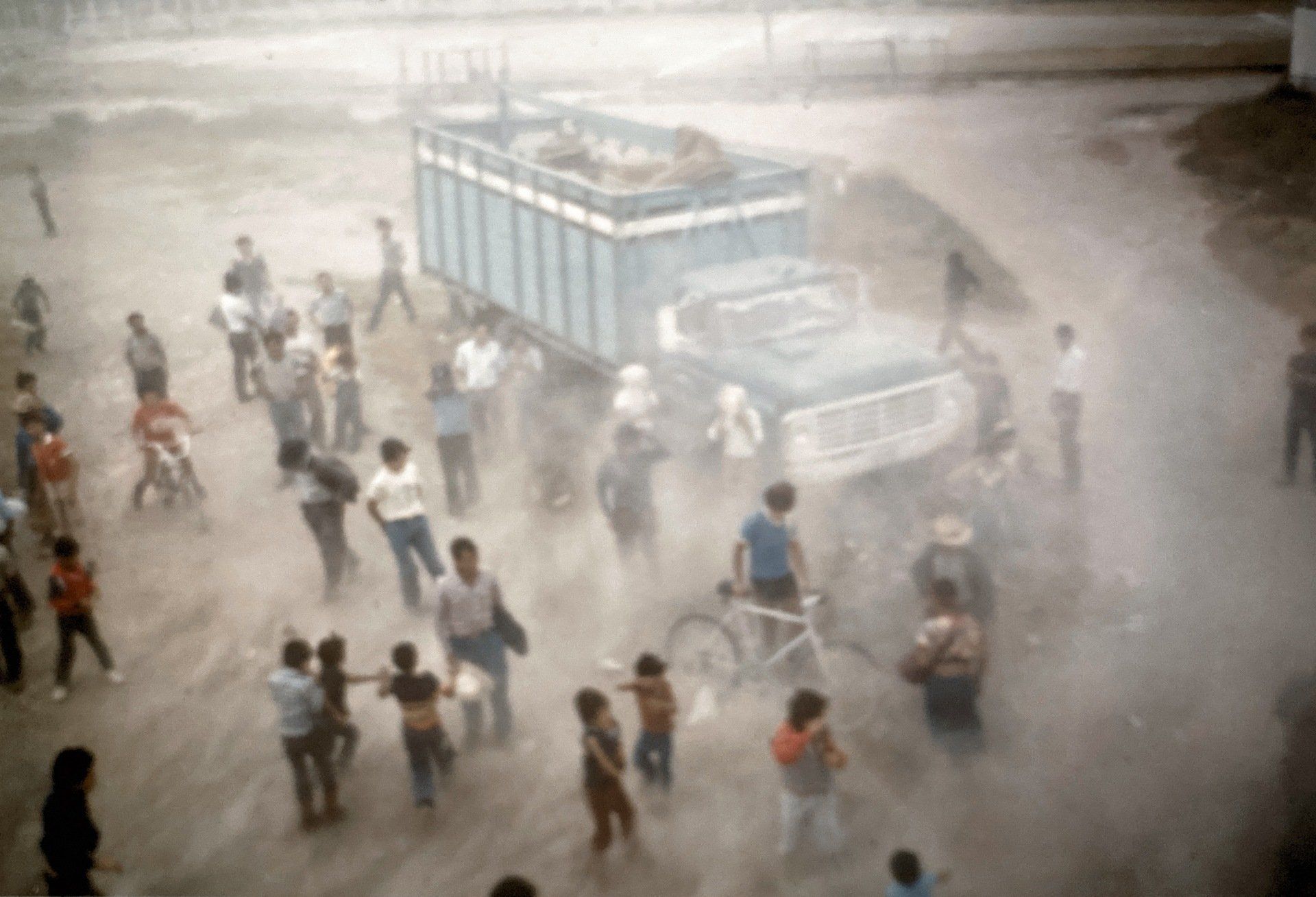 Eine Gruppe von Leuten steht auf einer unbefestigten Straße um einen Lastwagen herum.