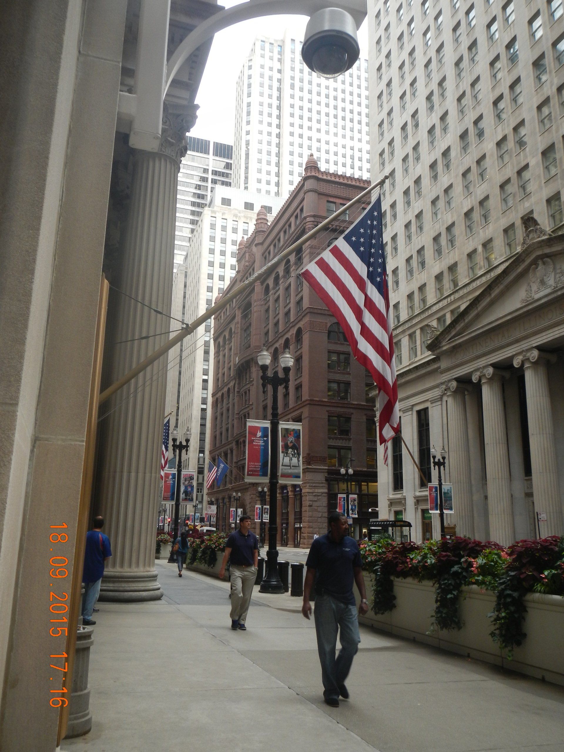 Ein Mann läuft einen Bürgersteig entlang, an einer Stange hängt eine amerikanische Flagge