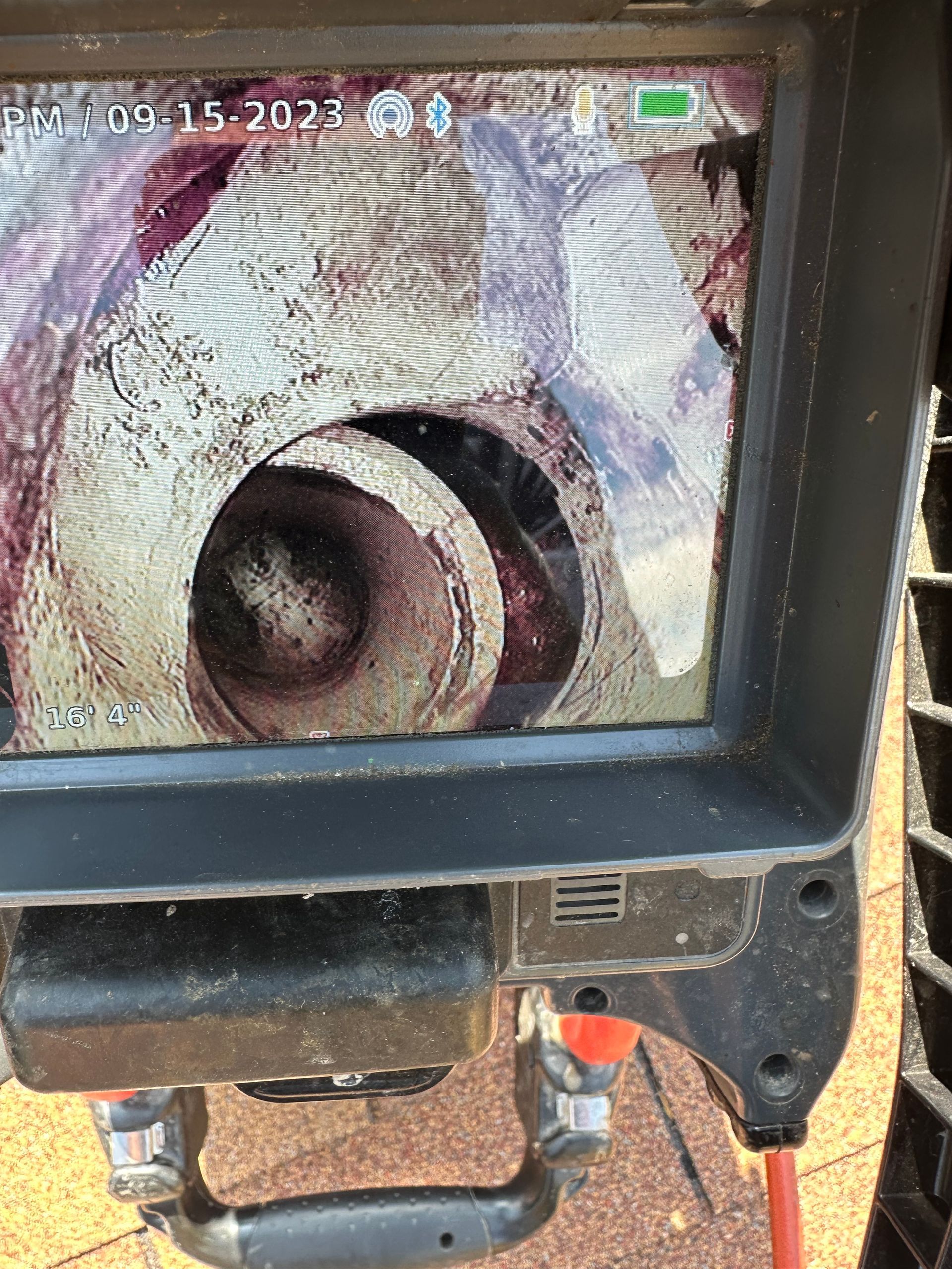 A monitor displays a view inside a pipe, likely for inspection, showing residue and the spiral form.
