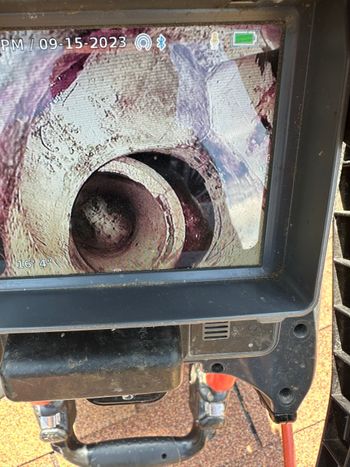 A monitor displays a view inside a pipe, likely for inspection, showing residue and the spiral form.