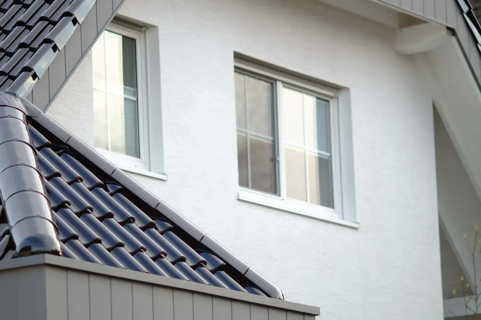 White house facade with two windows and a dark tiled roof