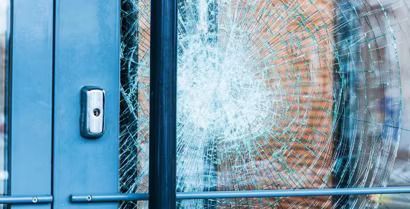 Blue door with a shattered glass window and visible cracks around the impact point