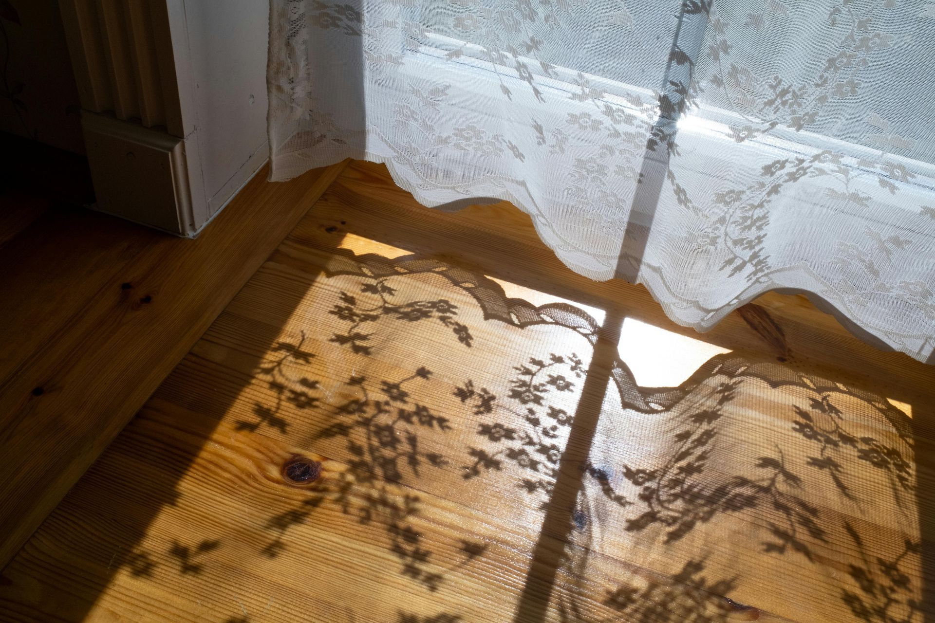sunlight filtering through a patterned window film, casting a soft glow on a hardwood floor - custom window film design