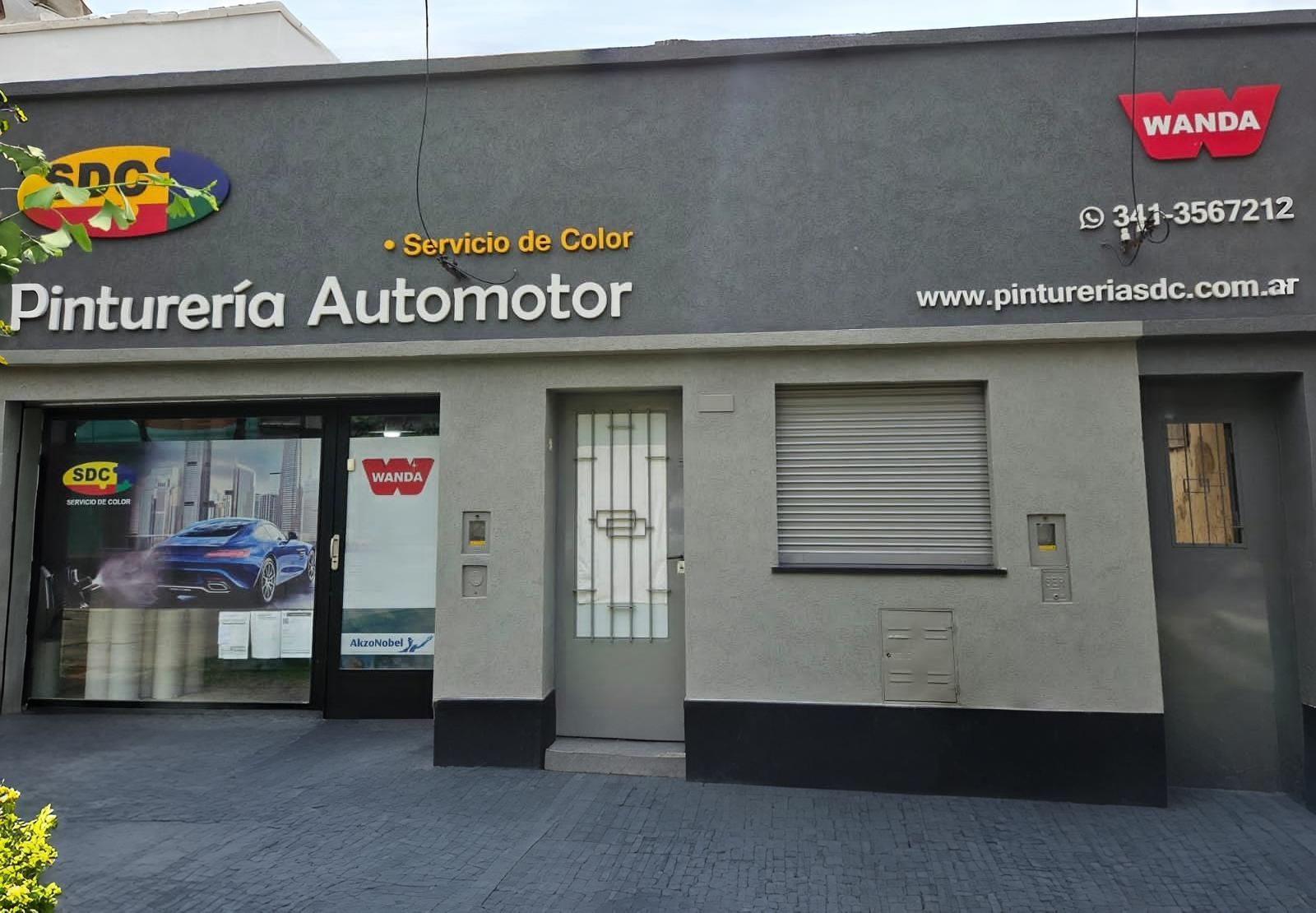 Exterior de un taller de pintura de automóviles. El edificio es gris con letreros de
