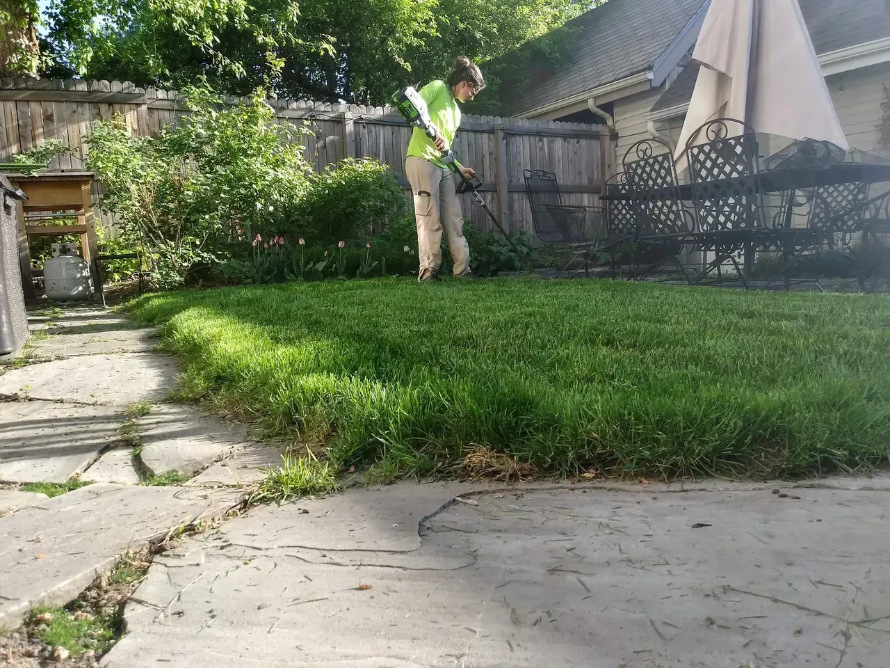 A man is cutting grass in a backyard with a lawn mower.