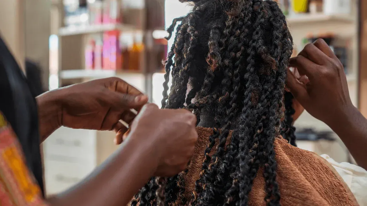 A woman is getting her hair braided in a salon.