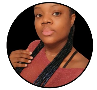 A woman with braids in her hair is wearing a pink sweater
