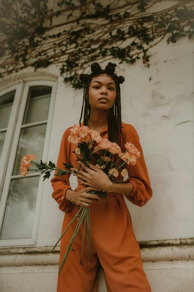 A woman in an orange jumpsuit is holding a bouquet of flowers.