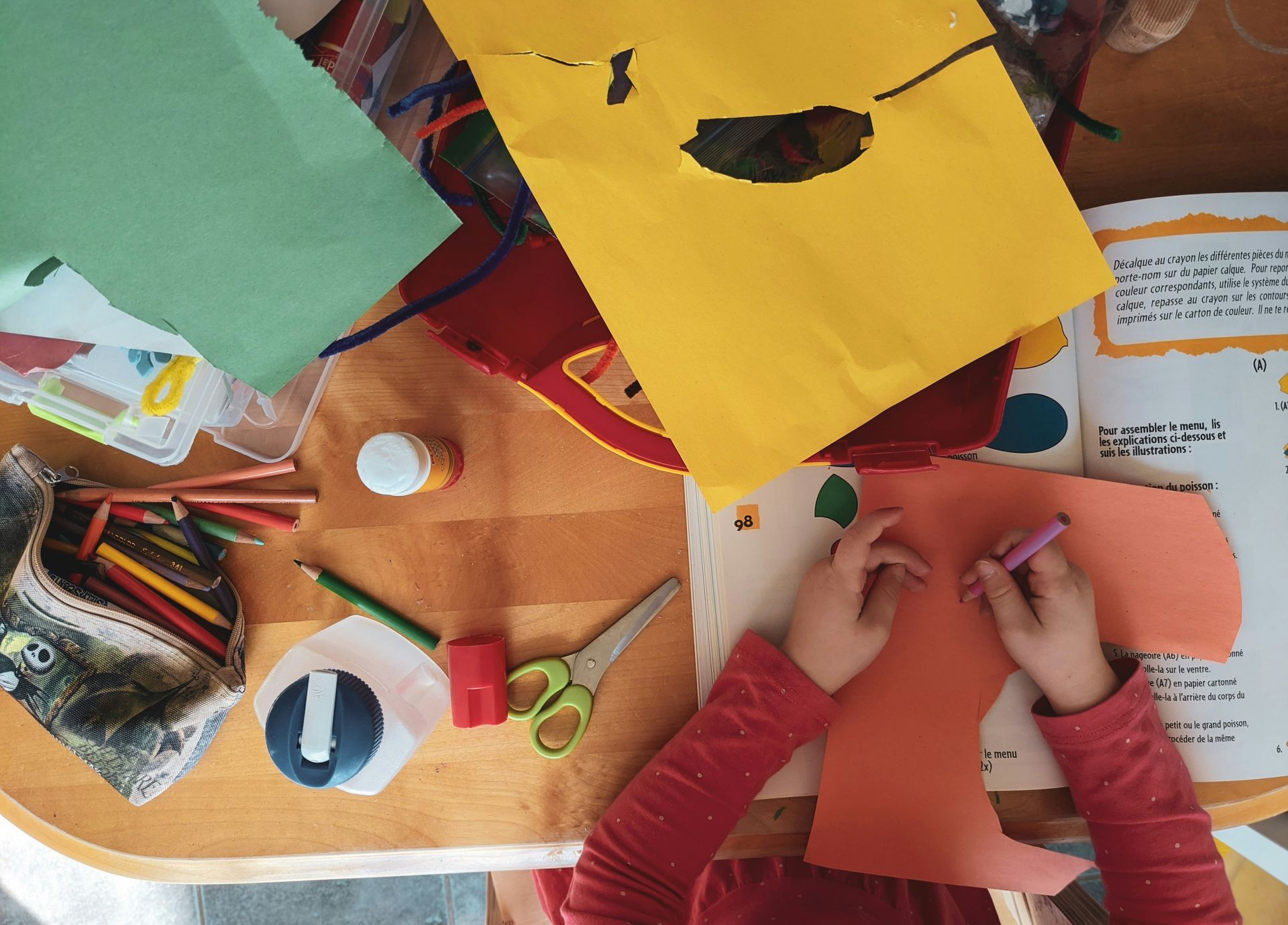 A child is sitting at a table making a craft