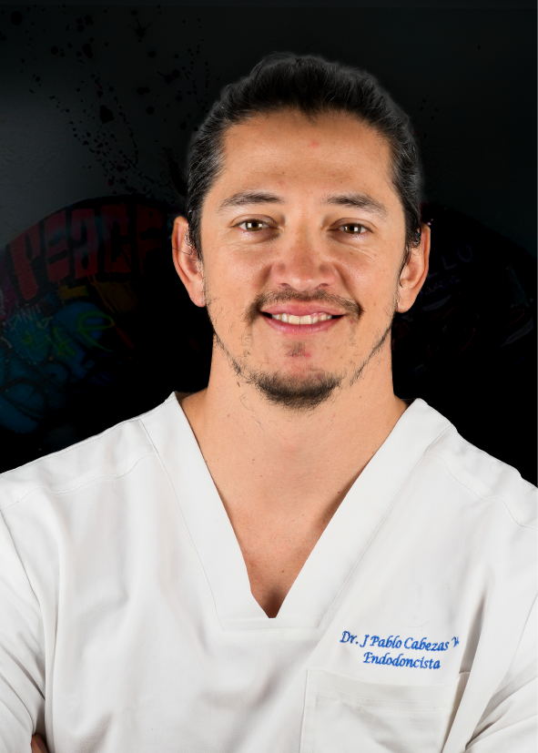 Un hombre con bata blanca sonríe, con el pelo recogido. Texto en la bata: