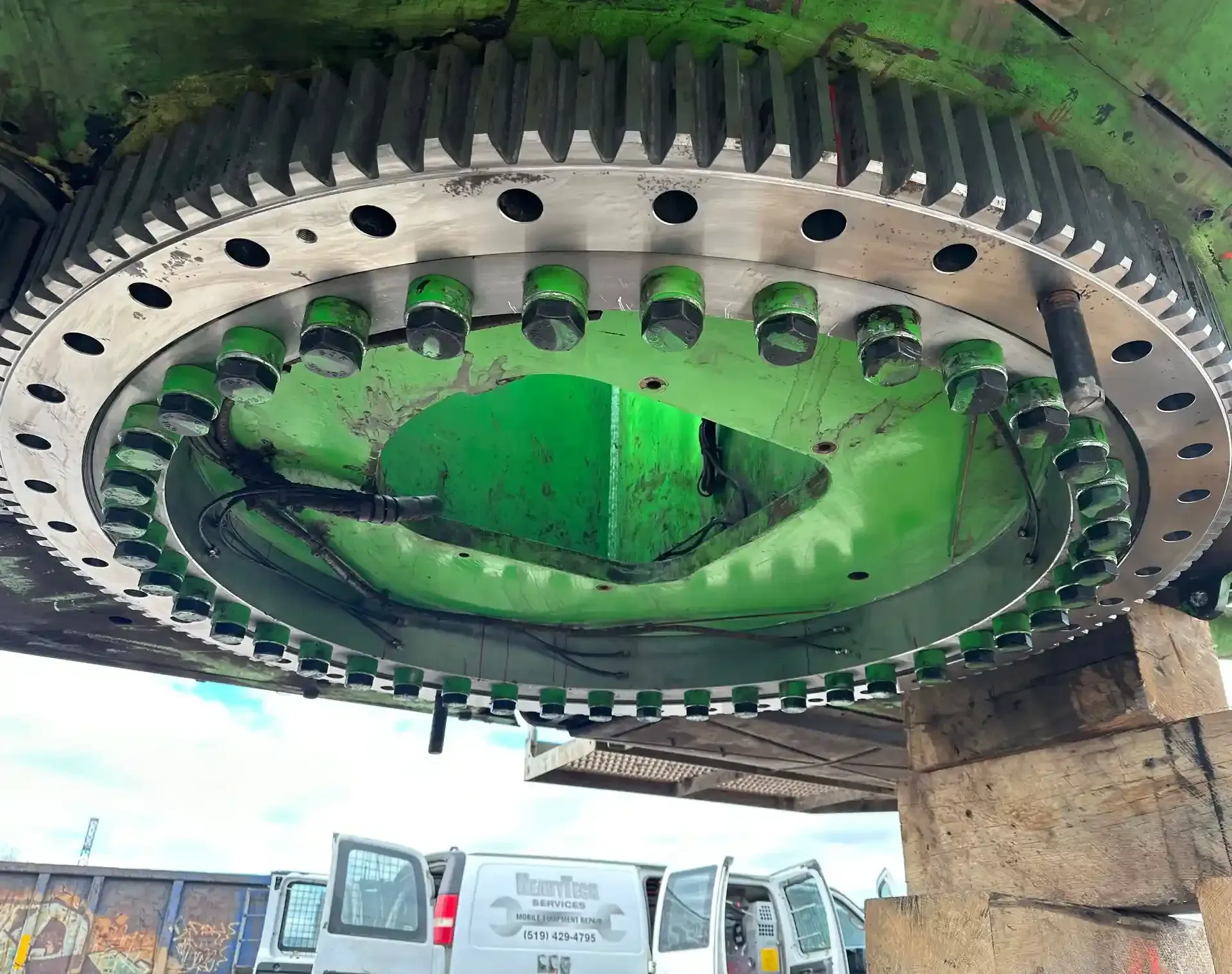 A large green gear is sitting on top of a wooden block.