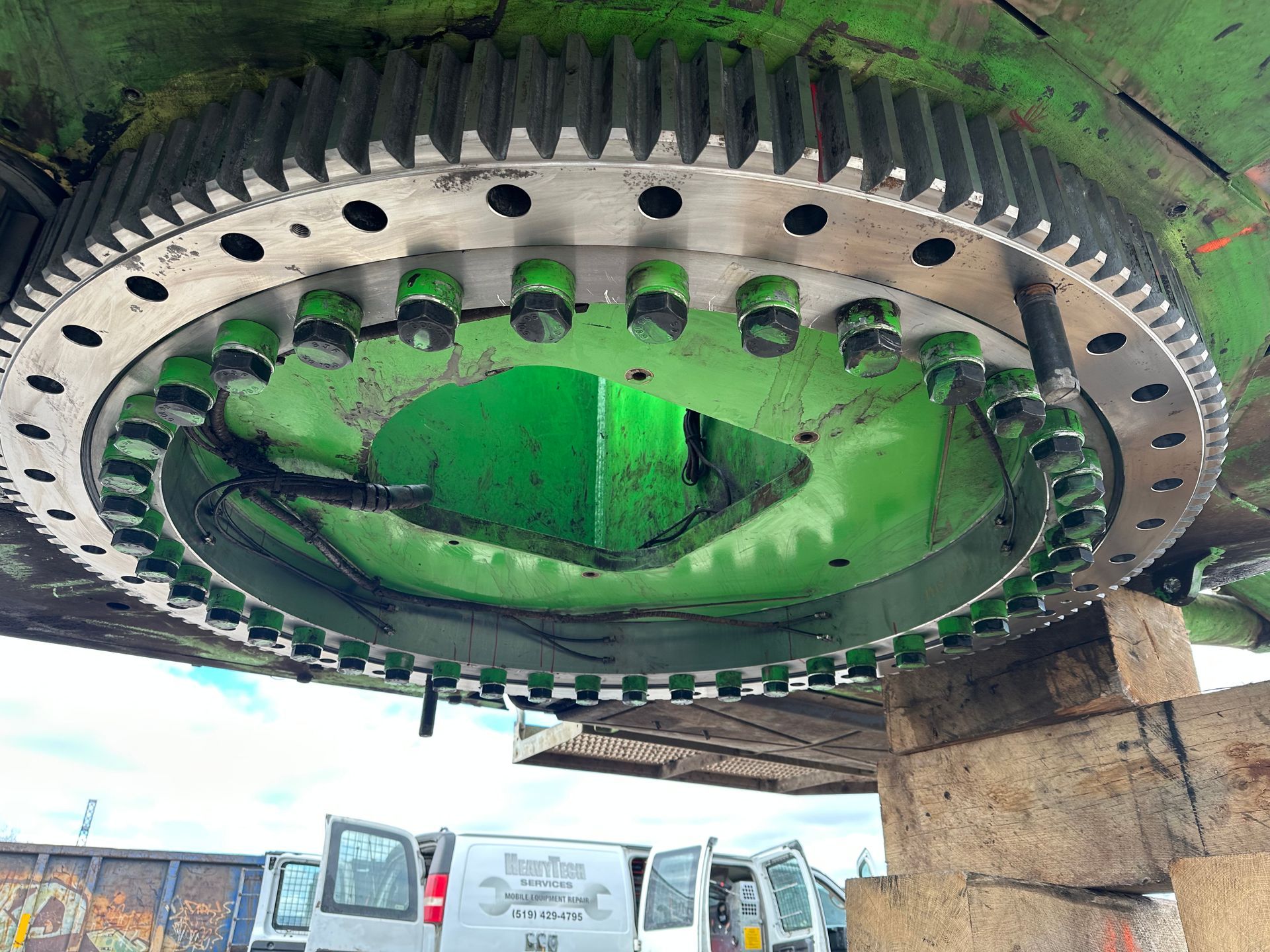 A large green gear is sitting on top of a white van.