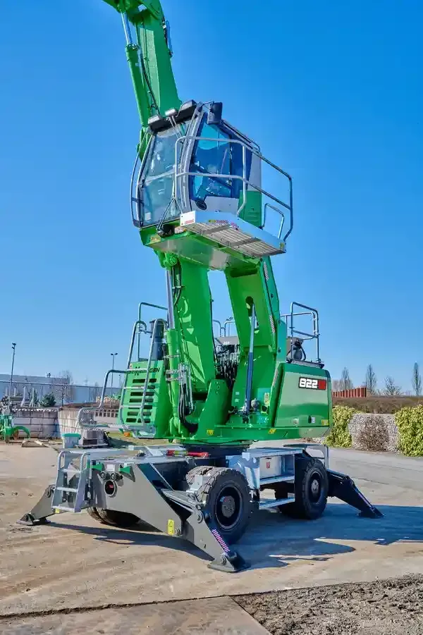 A green excavator is parked in a parking lot.