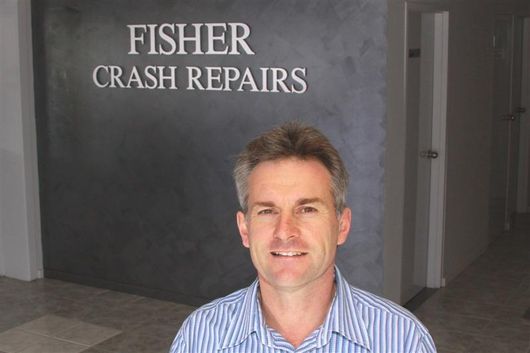 man standing in front of fisher crash repairs sign