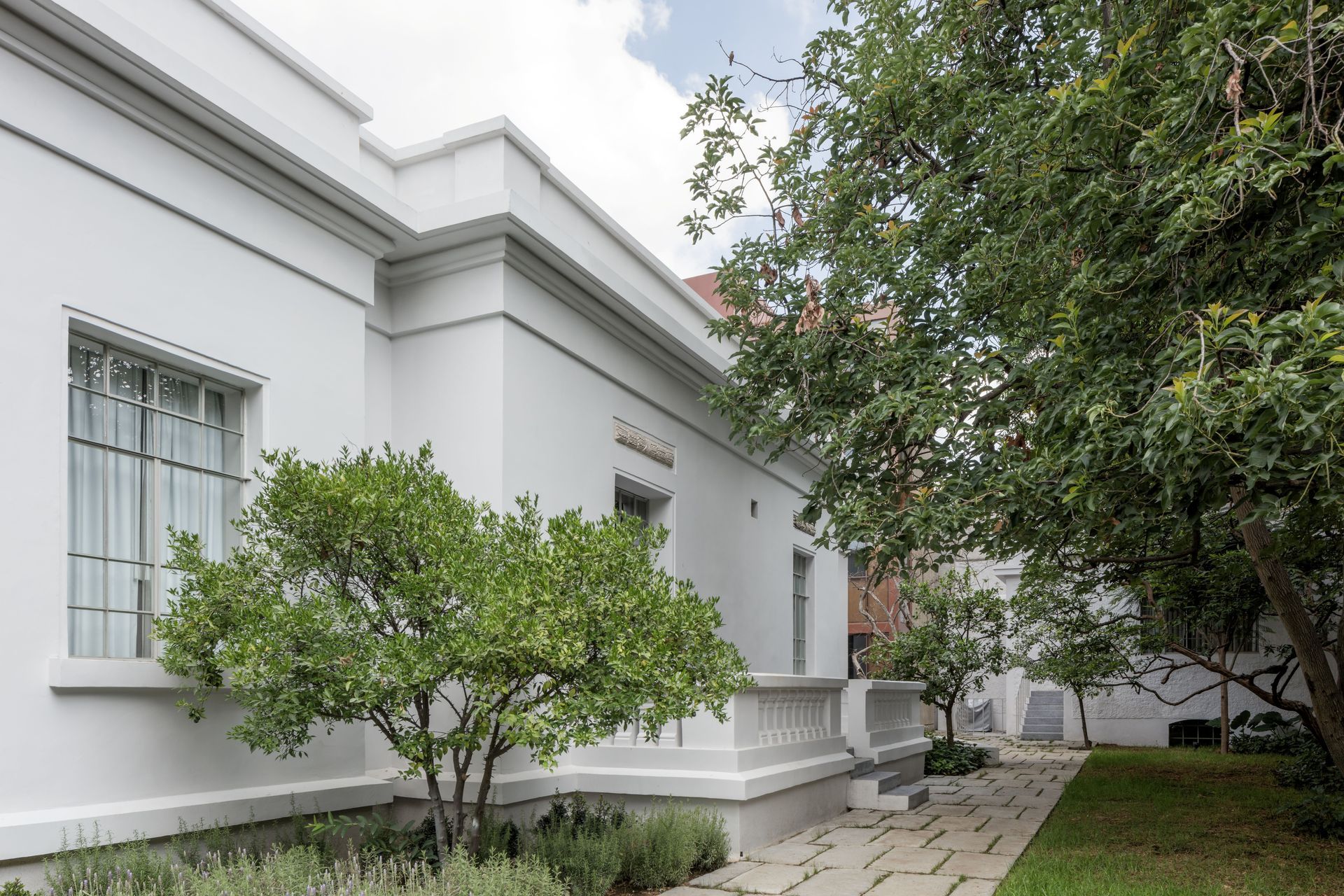 White building with trees and a walkway.