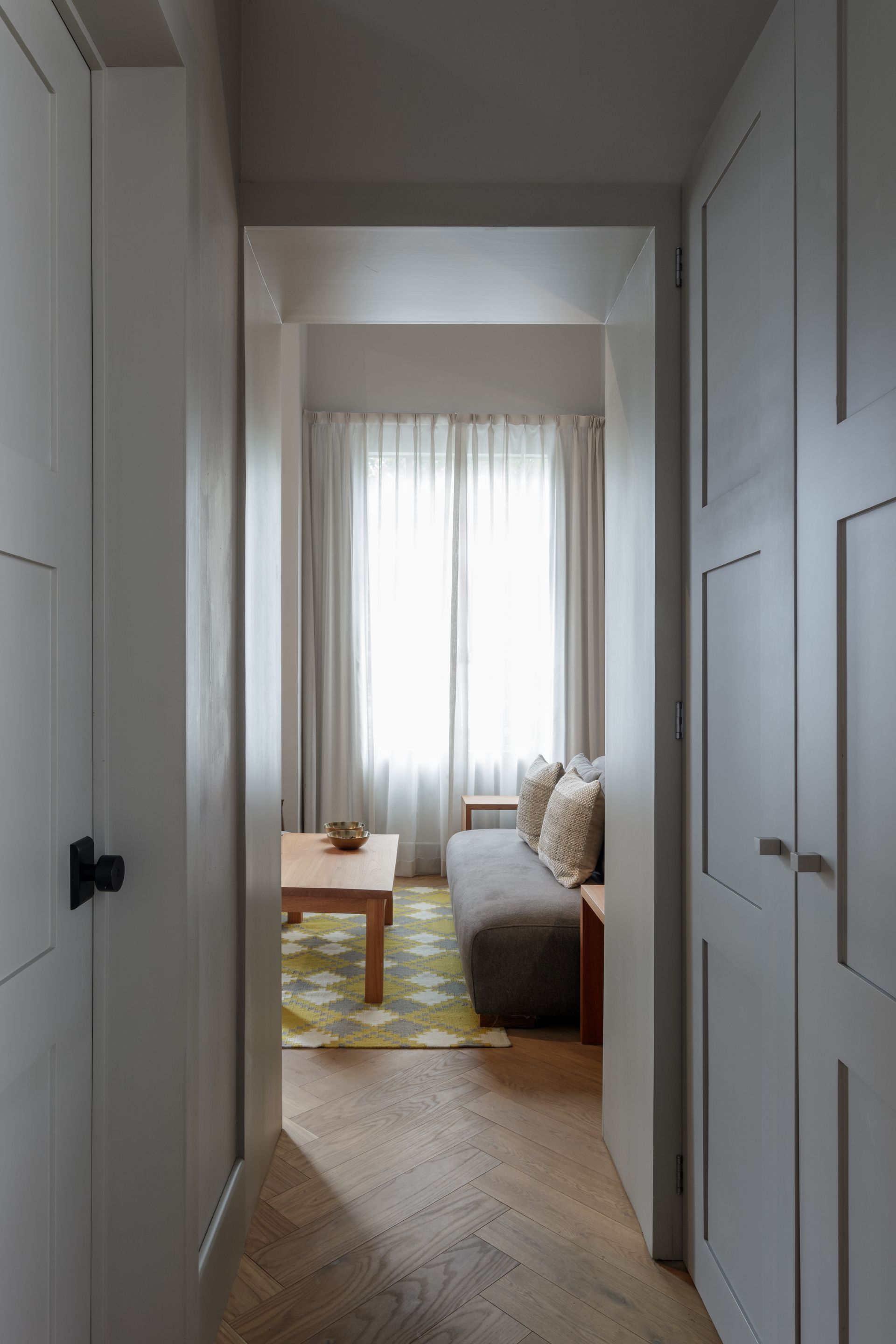 A hallway leading to a living room with a couch and a table.