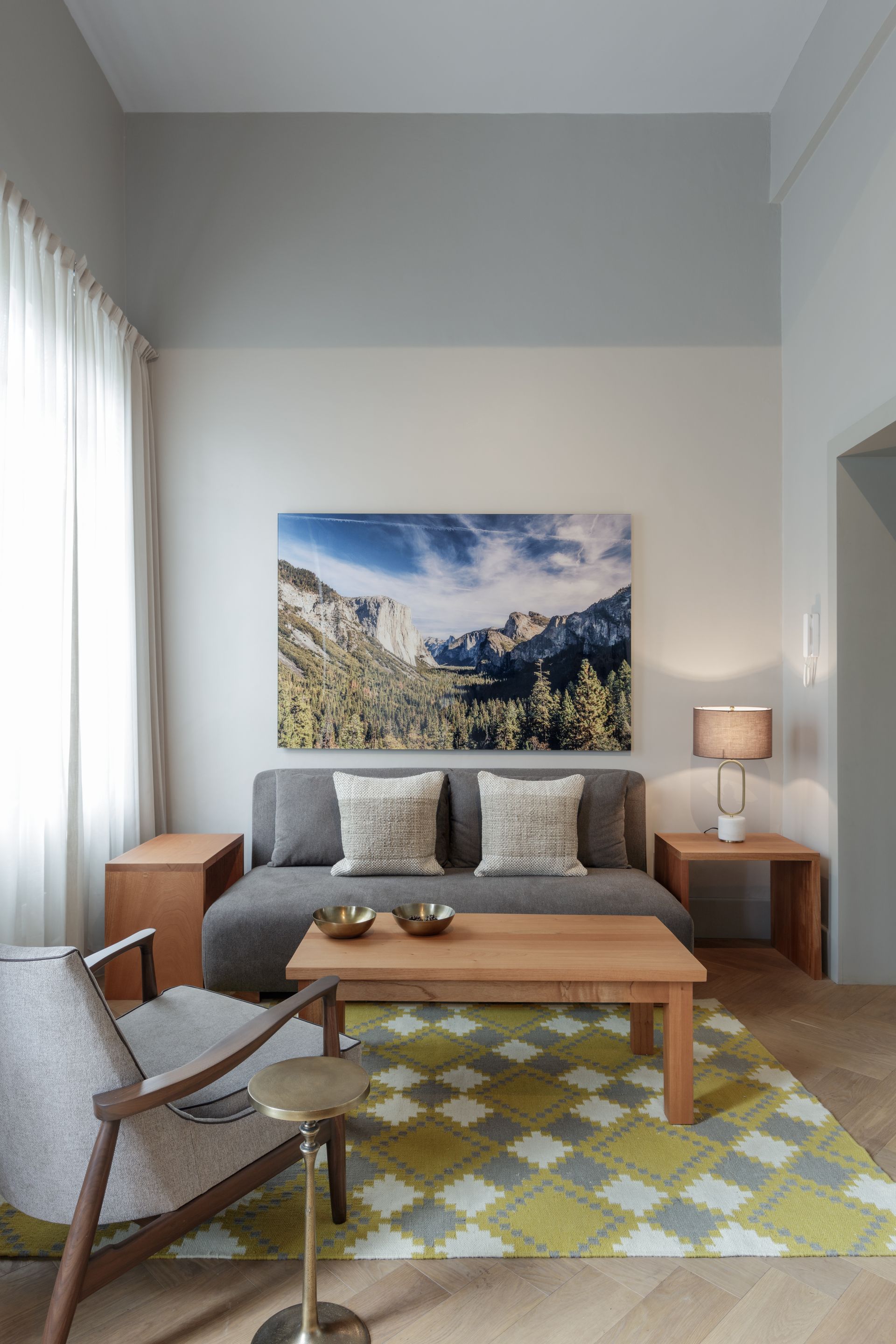 A living room with a couch , chair , coffee table and a painting on the wall.