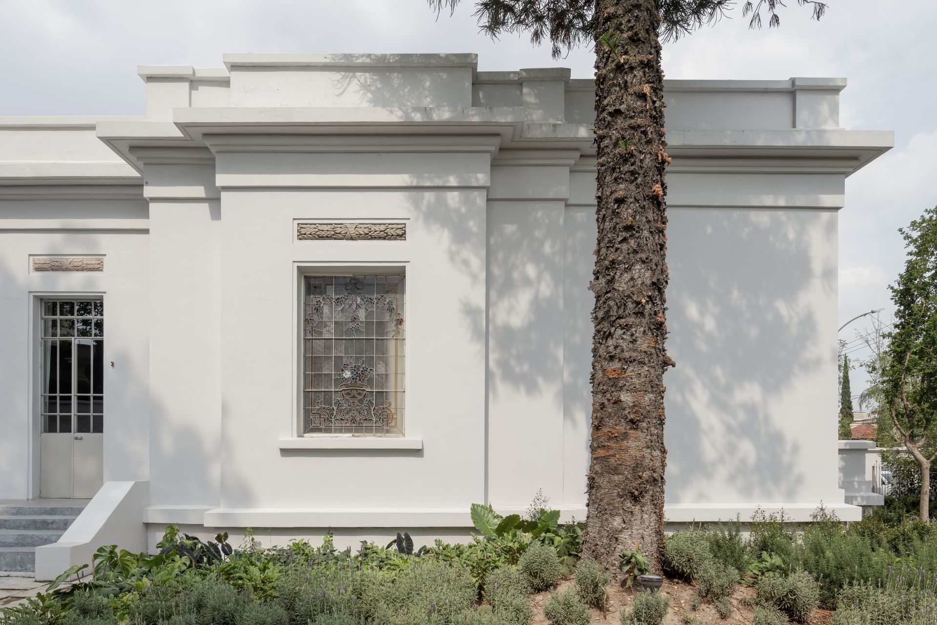 White building with rectangular design, ornate window, and palm tree.