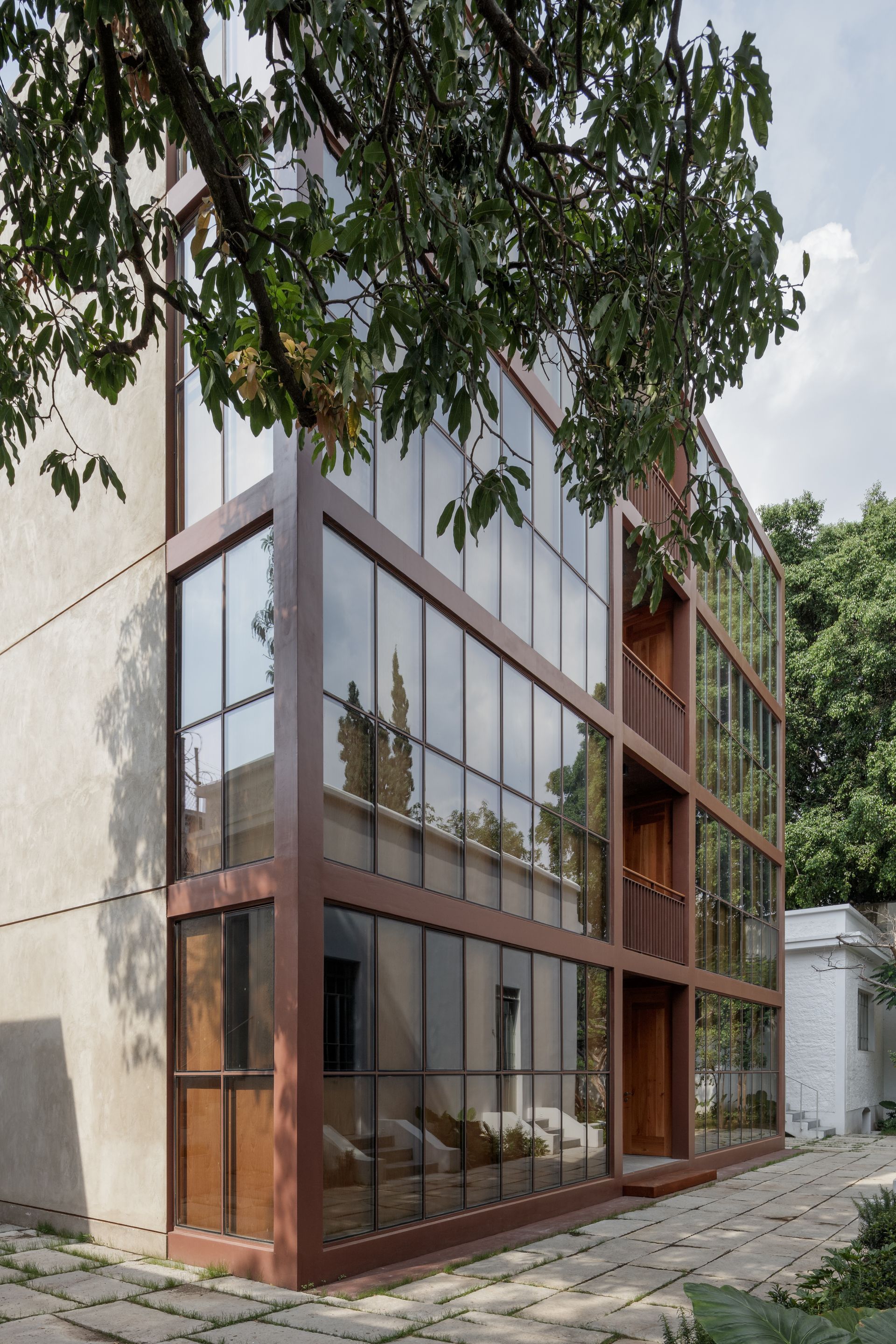 Modern building with brown frame and large glass windows, stone path.